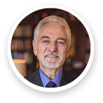 Dr Ivan Misner | Scion Social | Scion Social Portrait of a smiling older man with gray hair and a beard in a library setting, looking at the camera.